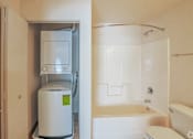 Thumbnail 9 of 13 - A bathroom with a toilet, tub, and a small refrigerator.