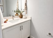 Thumbnail 19 of 31 - A white bathroom with a sink and a mirror.