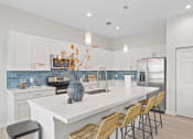 Thumbnail 16 of 37 - a kitchen with white cabinets and a large island with a white counter top