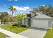 Thumbnail 6 of 37 - a house with a driveway and a garage with palm trees