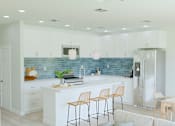 Thumbnail 10 of 14 - A kitchen with a blue backsplash and white cabinets.