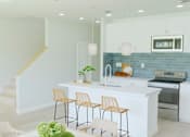 Thumbnail 9 of 14 - A kitchen with a white counter and bar stools.