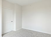 Thumbnail 21 of 44 - A white door is on the left of a room with white walls and carpeted floor at Sonder Point 50+ Apartments, Minnesota, 55430