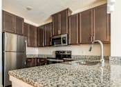 Thumbnail 8 of 41 - a kitchen with granite countertops and dark wood cabinets at Sonder House, Brooklyn Center