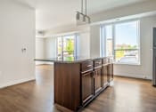 Thumbnail 26 of 44 - a kitchen and living room in an apartment with hardwood floors and a large window at Sonder Point 50+ Apartments, Brooklyn Center, MN, 55430