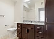 Thumbnail 13 of 44 - A white toilet sits in a bathroom with brown cabinets at Sonder Point 50+ Apartments, Brooklyn Center, 55430