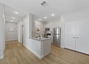 Thumbnail 18 of 23 - A kitchen with white cabinets and a wooden floor.