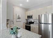 Thumbnail 16 of 23 - A kitchen with a stainless steel refrigerator, microwave, and oven.