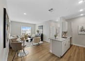 Thumbnail 22 of 23 - A well-lit, modern kitchen and dining area with wooden floors and white walls.