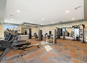 Thumbnail 9 of 12 - A gym with a variety of equipment including treadmills, weights, and exercise machines at Agave House Apartments, Arizona