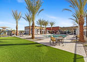 Thumbnail 8 of 12 - A pool surrounded by palm trees and a green lawn at Agave House Apartments, Casa Grande