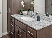 Thumbnail 14 of 40 - A bathroom with a sink, mirror, and wooden cabinets.at Decatur Landing I & II, Minnesota, 55445