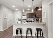 Thumbnail 10 of 40 - A kitchen with a granite countertop and bar stools.at Decatur Landing I & II, Brooklyn Park, 55445