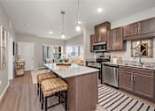 Thumbnail 37 of 40 - A kitchen with brown cabinets and a white island.at Decatur Landing I & II, Brooklyn Park Minnesota