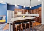 Thumbnail 19 of 33 - a kitchen with a large island with three stools at EastGate Apartments, Minnesota, 55904