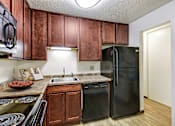 Thumbnail 8 of 25 - a kitchen with black appliances and wooden cabinets at Pheasant Park Apartments, New Hope, MN
