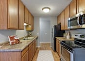Thumbnail 4 of 32 - A kitchen with wooden cabinets and a granite counter top at Heritage Hills Apartments, Minnesota, 55437