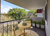 Thumbnail 15 of 32 - A balcony with a table and chairs overlooking a garden at Heritage Hills Apartments, Bloomington, MN