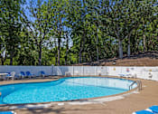 Thumbnail 17 of 32 - a swimming pool with chairs around it and trees in the background at Heritage Hills Apartments, Bloomington, 55437