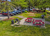 Thumbnail 32 of 32 - two picnic tables and benches in a park next to a parking lot at Heritage Hills Apartments, Bloomington