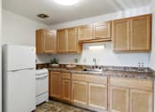 Thumbnail 9 of 21 - a kitchen with wooden cabinets and a white refrigerator at Humboldt Senior 55+ Apartments, Saint Paul, MN