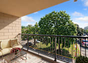 Thumbnail 13 of 21 - a balcony with a couch and a tree at Humboldt Senior 55+ Apartments, Minnesota, 55107