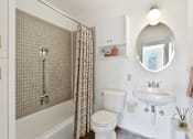 Thumbnail 12 of 21 - a white bathroom with a shower and a toilet and a sink at Humboldt Senior 55+ Apartments, Minnesota