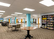 Thumbnail 16 of 21 - a large library with tables and chairs and bookshelves at Humboldt Senior 55+ Apartments, Saint Paul, MN, 55107