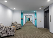 Thumbnail 17 of 21 - a long hallway with white and blue walls and a carpeted floor and some chairs at Humboldt Senior 55+ Apartments, Saint Paul, 55107