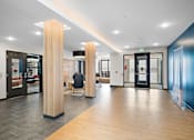 Thumbnail 16 of 19 - A hallway with a black chair and a wooden column at The Landing at Amber Fields Apartments, Rosemount, 55068