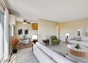 Thumbnail 2 of 14 - A living room with a white couch, a green chair, and a wooden coffee table at Northtown Village Apartments, Spring Lake Park