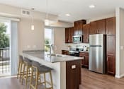 Thumbnail 3 of 27 - a kitchen with a large island and stainless steel refrigerator at The Quill 55+ Apartments, Hastings, MN