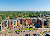 Thumbnail 43 of 44 - A large apartment complex with a parking lot in front at Sonder Point 50+ Apartments, Brooklyn Center, MN