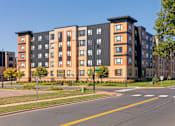 Thumbnail 44 of 44 - A large apartment building with a black and orange facade at Sonder Point 50+ Apartments, Brooklyn Center, Minnesota
