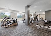 Thumbnail 34 of 44 - A gym with a row of treadmills and a row of stationary bikes.