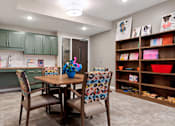 Thumbnail 41 of 44 - A kitchen with a table and chairs and a shelf with bowls on it at Sonder Point 50+ Apartments, MN