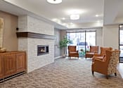 Thumbnail 40 of 44 - A living room with a fireplace and chairs at Sonder Point 50+ Apartments, Brooklyn Center