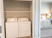 Thumbnail 13 of 51 - a room with a washer and dryer and a bedroom with a bed at Technology Park Apartments, Minnesota