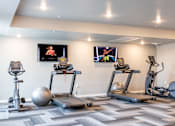 Thumbnail 19 of 51 - two treadmills and exercise balls in a gym with televisions at Technology Park Apartments, Minnesota