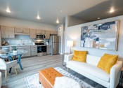 Thumbnail 33 of 51 - a living room with a couch and a table and a kitchen at Technology Park Apartments, Minnesota