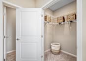 Thumbnail 14 of 44 - A white door is open to a bathroom with a toilet and storage baskets at The Winslow 62+ Apartments, Minnesota