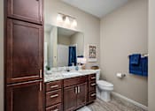 Thumbnail 15 of 44 - A bathroom with brown cabinets and a white toilet at The Winslow 62+ Apartments, Minnesota