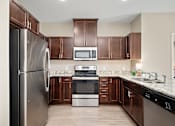 Thumbnail 4 of 44 - A kitchen with brown cabinets and a stainless steel refrigerator at The Winslow 62+ Apartments, West St Paul, 55118