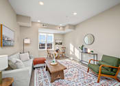 Thumbnail 5 of 44 - A living room with a white couch, a green chair, and a rug at The Winslow 62+ Apartments, West St Paul