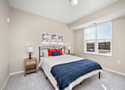 Thumbnail 8 of 44 - A bedroom with a bed, nightstand, and pictures on the wall at The Winslow 62+ Apartments, West St Paul, MN, 55118