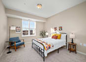 Thumbnail 12 of 44 - A bedroom with a bed, chair, and lamp at The Winslow 62+ Apartments, West St Paul, Minnesota