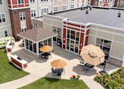 Thumbnail 26 of 44 - an aerial view of the courtyard of a building with tables and umbrellas at The Winslow 62+ Apartments, West St Paul, MN, 55118