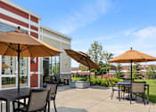 Thumbnail 29 of 44 - a patio with tables and umbrellas in front of a building at The Winslow 62+ Apartments, West St Paul, MN, 55118