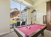 Thumbnail 32 of 44 - a pool table in a clubhouse with two lights hanging over it at The Winslow 62+ Apartments, West St Paul, Minnesota