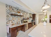 Thumbnail 33 of 44 - a kitchen with tiles on the wall and a white counter top at The Winslow 62+ Apartments, West St Paul, Minnesota